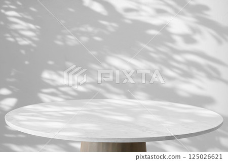Round marble table top with tree leaves shadow drop on white wall background for mockup product display 125026621