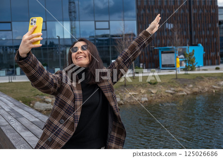 Woman Taking Selfie by Modern Building and Pond 125026686