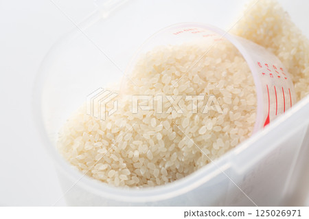 White rice in a rice bin and a measuring cup 125026971