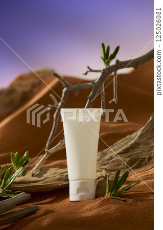 White tube placed on dry orange-brown sand in the hot desert. The tree trunk is rough and its branches are spindly and thorny. The sand dunes form undulating mountains behind. Night sky background.  125026981