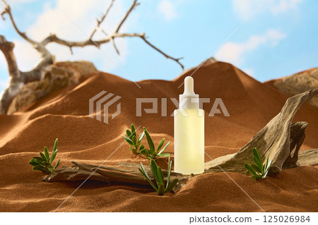 A transparent glass serum bottle sits on a rough and barren tree trunk. Tiny desert shrub grow from the dry sand. The sand forms small undulating hills behind. Blue sky with white clouds. A transparent glass serum bottle sits on a rough and barren tree trunk. Tiny desert shrub grow from the dry sand. The sand forms small undulating hills behind. Blue sky with white clouds. 125026984