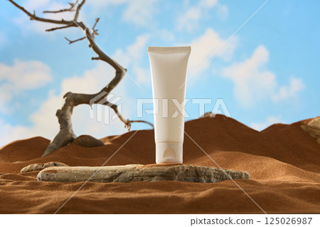 Unlabeled tube placed on a stone surface. The rock has rough edges with dark veins and cracks. Twisted tree branches grow from the arid desert. Pebbles are scattered around. Blue sky background. Unlabeled tube placed on a stone surface. The rock has rough edges with dark veins and cracks. Twisted tree branches grow from the arid desert. Pebbles are scattered around. Blue sky background. 125026987