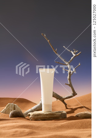 Unlabeled tube sits on a rock in the sandy desert landscape. The rocks have rough edges and irregular shape. A dry leafless tree with short branches, lying on the sand and reaching to the sky. Unlabeled tube sits on a rock in the sandy desert landscape. The rocks have rough edges and irregular shape. A dry leafless tree with short branches, lying on the sand and reaching to the sky. 125027000