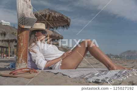 Woman relaxing on beach reading book enjoying summer meditation time Woman relaxing on beach reading book enjoying summer meditation time 125027192