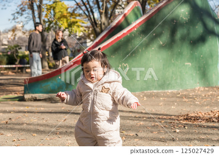 [一名 1 歲的孩子站在落葉覆蓋的冬季公園玩耍] 125027429