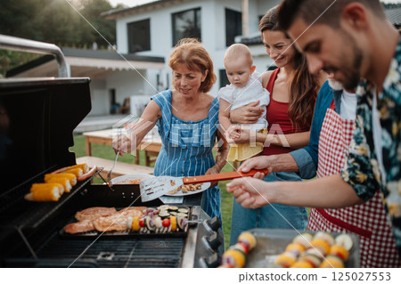 Three generations of family preparing food for a spring weekend barbecue. 125027553