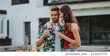 Married couple enjoying glass of wine together at family gathering. 125027555