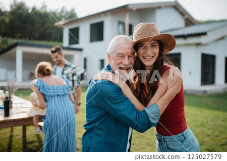 Senior father with daughter outdoors in backyard, looking at camera. 125027579