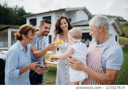 Three generations of family preparing food for a spring weekend barbecue. 125027614