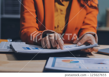 Businesswoman or accountant working Financial investment on calculator, calculate, analyze business and marketing growth on financial document data graph, Accounting, Economic, commercial concept. 125027655