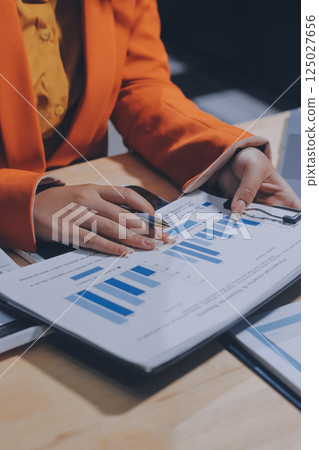Businesswoman or accountant working Financial investment on calculator, calculate, analyze business and marketing growth on financial document data graph, Accounting, Economic, commercial concept. 125027656