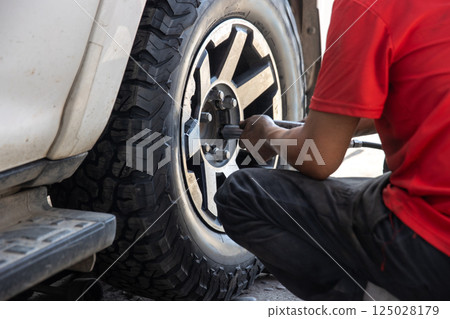 Mechanic changing a wheel of a modern car Mechanic changing a wheel of a modern car 125028179