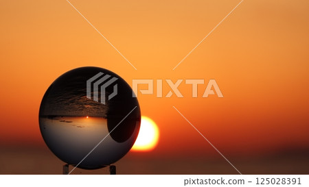 Glass ball and the sun setting over the sea 125028391