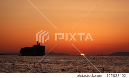 Cargo ship and the sun setting over the sea Cargo ship and the sun setting over the sea 125028402