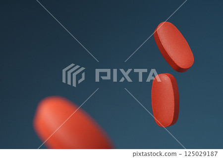 Red oval tablets on a blue background. Advertising banner with space for text. The concept of health. 125029187
