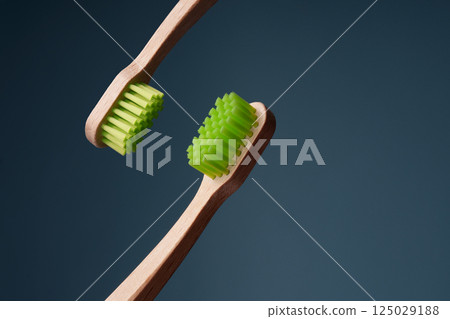 Two wooden toothbrushes with green shield on blue background. Environmental friendliness. Two wooden toothbrushes with green shield on blue background. Environmental friendliness. 125029188