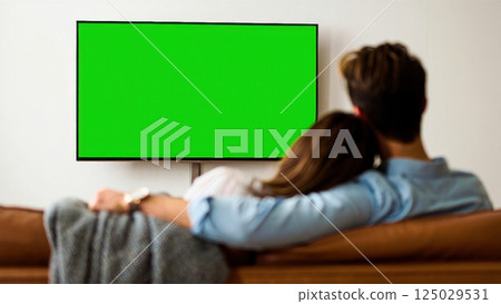 Happy couple watching tv with the green screen on it, photo for keying 125029531