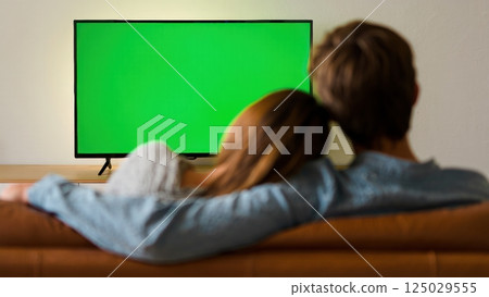 Happy couple watching tv with the green screen on it, photo for keying 125029555