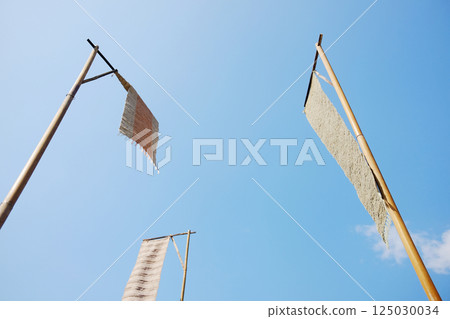 Tung flag on a bamboo pole with blue sky is the arts and culture in northern of Thailand Tung flag on a bamboo pole with blue sky is the arts and culture in northern of Thailand 125030034