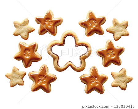 Delicious starshaped cookies, some glazed with caramel, arranged around a cookie cutter.  A festive, sweet image perfect for blogs, holiday baking websites, or food publications. 125030415