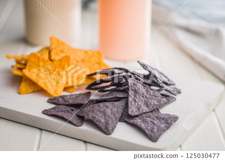 Dark and yellow nachos chips on white table. 125030477
