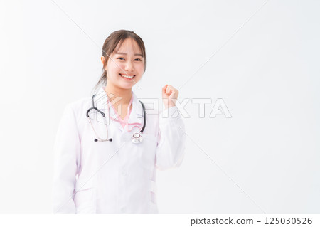 A trainee doctor in a white coat posing with a fist in the air on a white background A trainee doctor in a white coat posing with a fist in the air on a white background 125030526