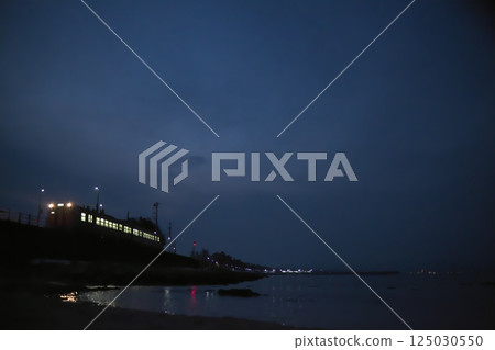 A local train running along the seaside at night 125030550