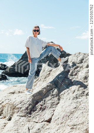 Beautiful woman in summer clothes walking on the beach by the sea 125030762