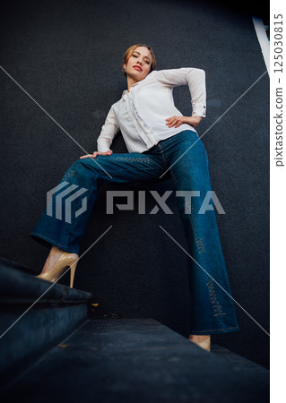 Portrait of a beautiful woman fashionably in jeans on a dark background 125030815