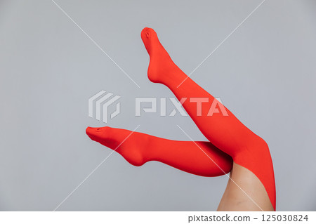 Slender long female legs in red stockings, tights on a white background Slender long female legs in red stockings, tights on a white background 125030824