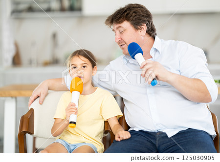 Karaoke time - father and daughter sing into microphones 125030905