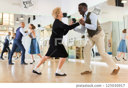 Lady learning to dance lindy hop with man in dance school Lady learning to dance lindy hop with man in dance school 125030917