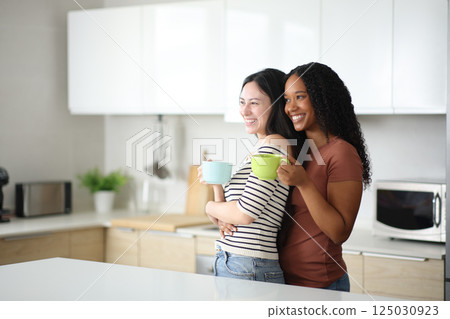 Lesbian interracial couple in the kitchan at breakfast 125030923