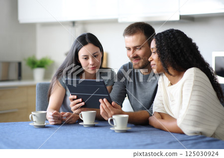 Interracial roommates watching videos on tablet 125030924