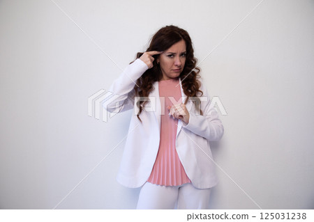 Brunette woman holding her finger at her head on white office background 125031238