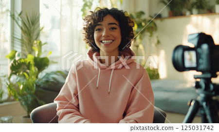 Smiling content creator recording a video in a cozy home studio 125031742