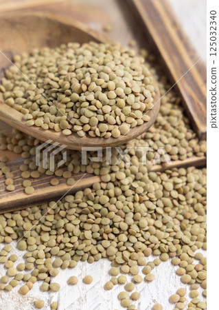 Bowl full of dried raw green lentils on white table closeup. Vegetarian food, mediterranean legumes Bowl full of dried raw green lentils on white table closeup. Vegetarian food, mediterranean legumes 125032340