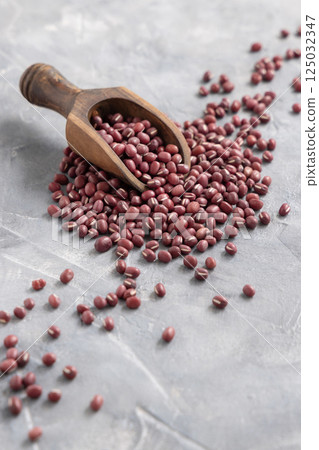 Scoop full of dried azuki beans on gray closeup. East Asian legumes, vegetarian protein source Scoop full of dried azuki beans on gray closeup. East Asian legumes, vegetarian protein source 125032347