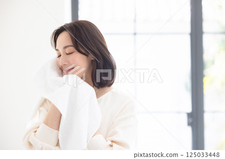 Woman holding a towel over her cheek 125033448
