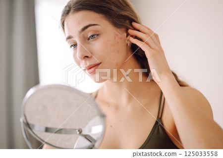 Woman worry about her face when she saw the problem of acne occur by a mini mirror. Pimples, acne 125033558