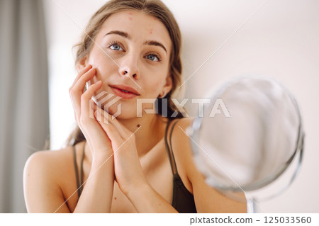 Woman worry about her face when she saw the problem of acne occur by a mini mirror. Pimples, acne 125033560