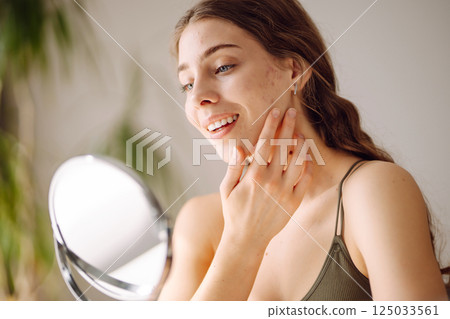 Woman worry about her face when she saw the problem of acne occur by a mini mirror. Pimples, acne Woman worry about her face when she saw the problem of acne occur by a mini mirror. Pimples, acne 125033561