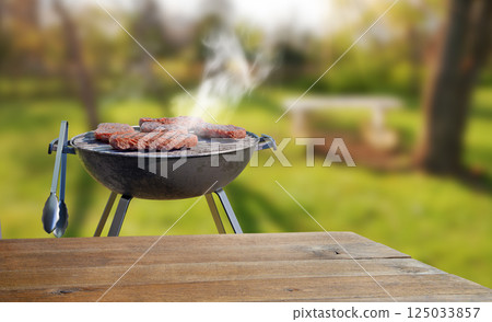 summer time in backyard garden with grill BBQ, wooden table, blurred background 125033857