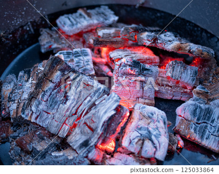 Glowing embers of burning wood in a fire pit, texture of the charcoal and ashes in grill Glowing embers of burning wood in a fire pit, texture of the charcoal and ashes in grill 125033864