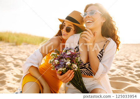 Two beautiful women enjoying on the beach. Female friends walking on the beach. Lifestyle concept. Two beautiful women enjoying on the beach. Female friends walking on the beach. Lifestyle concept. 125033954