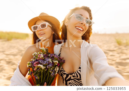 Two pretty friends women making selfie on beach, light and bright summer colors. Friends together Two pretty friends women making selfie on beach, light and bright summer colors. Friends together 125033955
