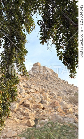Ras Al Khaimah,UAE - March 29,2025 : Watchtower caps rocky mound while tower blends with stone layers, watchtower represents lookout heritage, tourist destination, attraction  125034045