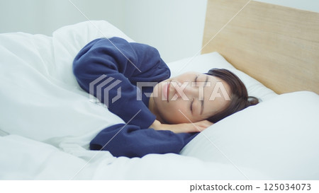 A woman sleeping in bed 125034073