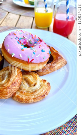 Sweet selection highlights playful donut with pastel frosting, golden pastries shimmer with soft texture, joyful breakfast scene evokes light-hearted indulgence and morning delight Sweet selection 125034118