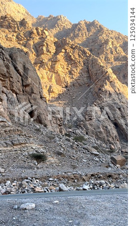Rugged mountain journey reveals crumbling stone walls as rugged mountain journey cuts through desert, showcasing traditional structure as cultural tourist attraction carved by time. 125034144